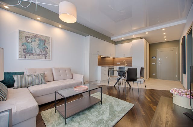 living space with a neutral colored couch table and kitchenette with hardwood floors